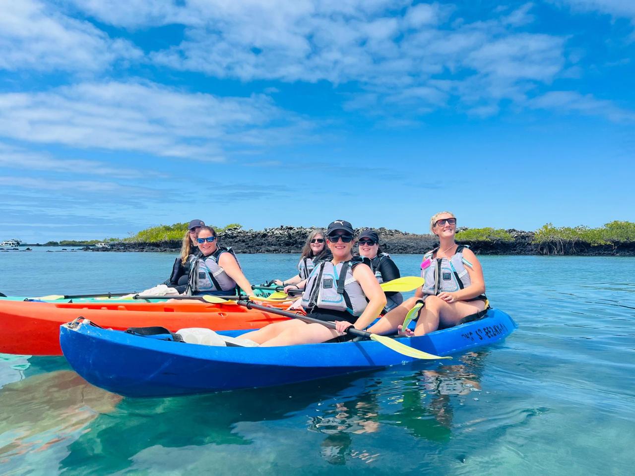Travelers kayaking through clear water in the Galapagos Islands
